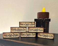 a candle that is sitting on top of some wood blocks with words written on it