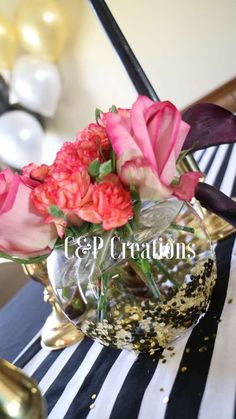 a vase filled with pink and red flowers on top of a table next to balloons