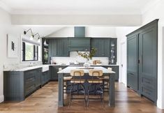 a large kitchen with wooden floors and green cabinets