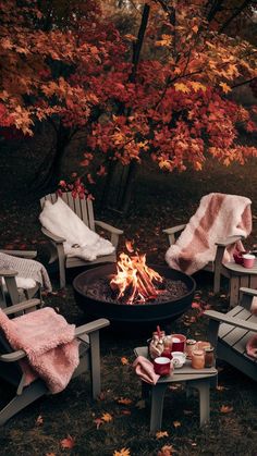 an outdoor fire pit surrounded by chairs and blankets