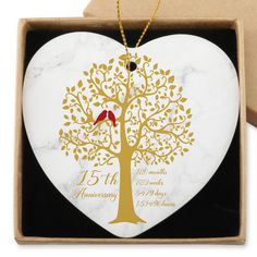 a marble heart shaped ornament with a gold tree and red bird on it