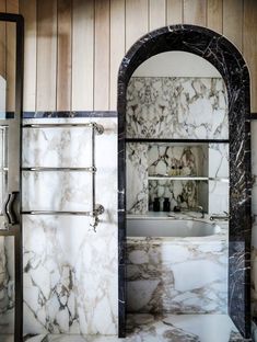 a bathroom with marble walls and flooring next to a bathtub in the corner