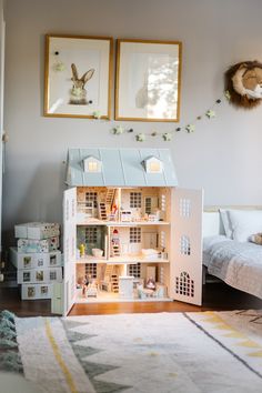 a doll house sitting on top of a wooden floor next to a bed and dresser