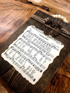 an old sheet of music is displayed on a wooden board with string and beads around it