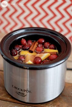 a crock pot filled with fruit on top of a wooden table