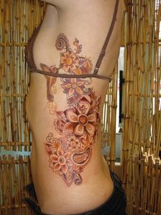 a woman's lower back tattoo with flowers on her stomach and an intricate design