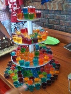 three tiered trays filled with different colored cups on top of a wooden table