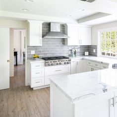 a large kitchen with white cabinets and marble counter tops, along with an island in the middle