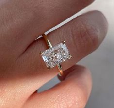 a woman's hand with a gold ring and a diamond in the shape of a square