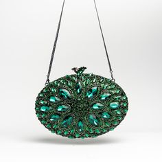 Description: Add a touch of elegance to your evening ensemble with this stunning emerald-green crystal clutch. Encrusted with dazzling crystals that create a mesmerizing leaf pattern, this bag is a true statement piece. The intricate design features a mix of deep green and light green crystals, meticulously arranged to catch the light from every angle. The metallic silver frame adds a sophisticated contrast, while the silver chain allows for versatile wear as a shoulder bag or crossbody. The int Elegant Green Evening Bag With Rhinestones, Green Rhinestone Party Evening Bag, Glamorous Green Evening Bag, Green Elegant Evening Bag, Elegant Green Evening Bag For Events, Elegant Green Evening Bag For Event, Green Crystal Jewelry For Evening, Elegant Green Clutch, Green Evening Jewelry