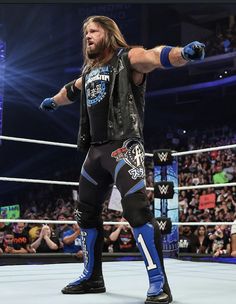 a man with long hair standing in the middle of a wrestling ring