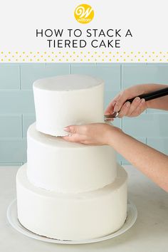 a woman is decorating a tiered cake