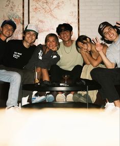 a group of young people sitting on top of a black couch next to each other