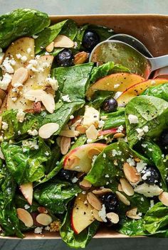 a salad with spinach, apples, almonds and blueberries in a bowl