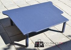 a blue coffee table sitting on top of a brick floor next to a bag and purse