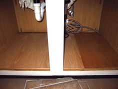 the bottom half of a cabinet with wires in it and an outlet on the floor