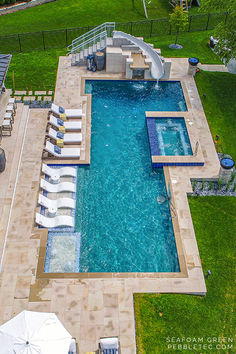 an aerial view of a swimming pool with lounge chairs and umbrellas in the grass