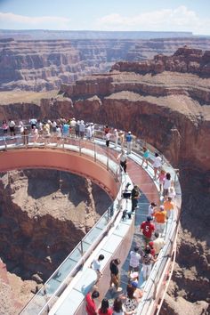 people are standing on the edge of a bridge in the grand canyon, looking down