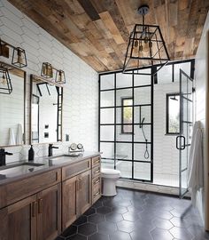 a bathroom with wood and glass walls, black tile flooring and wooden accents on the ceiling