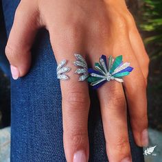 a woman's hand with two rings on her fingers and one ring is decorated with leaves