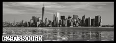 black and white photograph of new york city skyline from across the water with reflections in the water