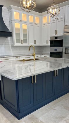 a large kitchen with white cabinets and blue counter tops, gold faucet handles