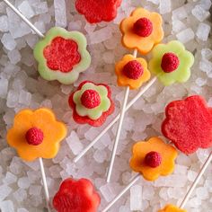 there are many colorful lollipops on the stick with raspberries and flowers