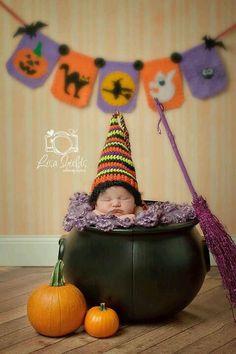 a baby in a witches hat is sleeping in a caulder next to pumpkins