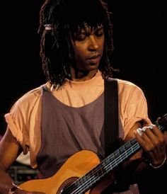 a man with dreadlocks playing an acoustic guitar