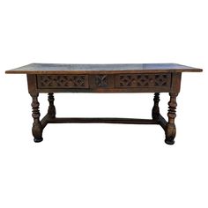 an old wooden table with two drawers on one side and carvings on the other end