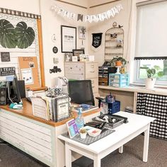 an office with desks, shelves and pictures hanging on the wall above it's windows