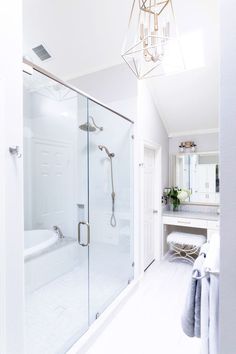 a bathroom with a walk in shower next to a white sink and toilet under a chandelier