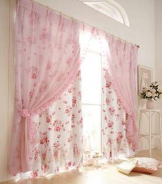 a window with pink curtains and flowers on the drapes, in front of a white wall