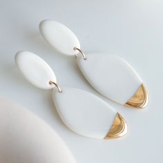 two white and gold earrings sitting on top of a table