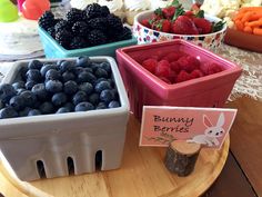 there are many different types of berries in the trays on this wooden table, including blueberries and raspberries