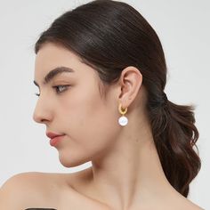 This pair of earrings features a lustrous solitaire shell pearl and a radiant gold hoop, creating a harmonious balance of classic and modern. The delicate huggie hoop is adorned with brilliant pavé set zirconia, adding a touch of sparkle and glamour that beautifully complements the pearls. These earrings effortlessly transition from day to night, from casual to formal events. Whether you're attending a wedding, a dinner party, or simply adding a touch of luxury to your everyday attire, these ear Modern Pearl Charm Earrings For Everyday, Modern Everyday Earrings With Pearl Charm, Modern White Round Pearl Earrings, Modern Yellow Gold Hoop Earrings With Pearl Drop, White Pearl Huggie Hoop Earrings, Elegant White Huggie Earrings For Everyday, Modern White Huggie Earrings For Everyday, Modern Round Pearl Earrings With Pearl Charm, Modern Pearl White Earrings With Pearl Charm