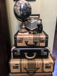 three suitcases stacked on top of each other in front of a wall with a globe