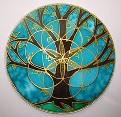 a glass plate with a tree painted on the front and sides in gold, blue and green