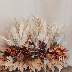 an arrangement of dried flowers and leaves on a table