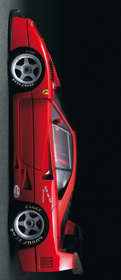 the rear end of a red sports car with its hood up and wheels down, seen from above