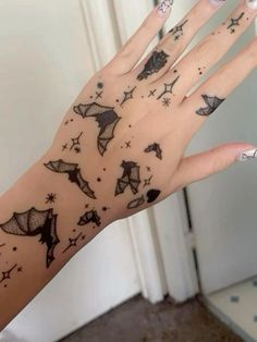 a woman's hand with tattoos on it and stars in the sky above her