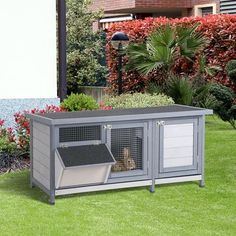 an outdoor dog house with a cat in it's cage on the grass outside