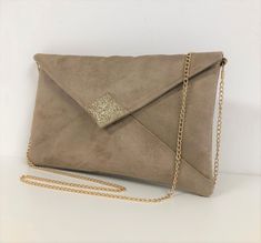 "A beige wedding clutch bag with golden sequins, in suede with a very velvety feel, with a stitched yoke on the front.  The tip of the flap is covered with gold glitter fabric. Two options are possible: WITH or WITHOUT removable shoulder chain, the choice is yours! Gold chain shoulder strap: This one is very easily removable and your bag will become a clutch! (length 120 cm) This handbag flap envelope shape, will be very trendy for your outings, a wedding, bridesmaids or a ceremony. It will easily contain your essential phone, makeup, keys, glasses, papers .... It is lined with printed cotton fabric coordinated. The very nice quality of the suede, which is also canvas, ensures a very good hold. The closing of the flap is done by a golden magnetic button. It is scratched inside \"Lesfilsdis Wedding Clutch Bag, Unique Envelopes, Beige Wedding, Clutch Bag Wedding, Tablet Bag, Wedding Clutch, Shoulder Chain, Ladies Clutch, Glitter Fabric