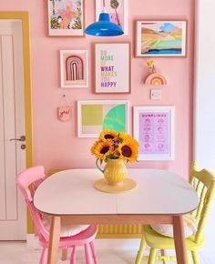 a dining room with pink walls and pictures on the wall