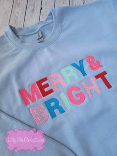 This Merry & Bright Sweatshirt will be the envy of all your festive friends. It's colorful, trendsetting and perfect for your Christmas wardrobe. Available in pink, grey or blue, this stylish sweatshirt is sure to bring some seasonal cheer! All of my items are made to order, if you have any questions please don't hesitate to ask! Pink Tops With Embroidered Graphics For Winter, Blue Winter Sweater With Embroidered Text, Embroidered Blue Winter Tops, Winter Blue Sweater With Embroidered Text, Pink Cotton Holiday Sweatshirt, Christmas Cotton Top With Embroidered Text, Festive Holiday Cotton Sweater, Fun Cotton Sweatshirt For Winter, Holiday Embroidered Cotton Top