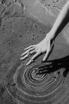 a person reaching for something in the sand with their hand on it's side