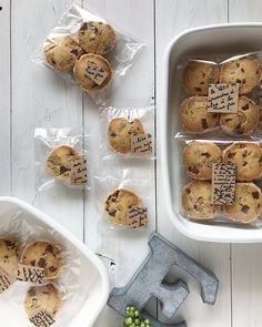 chocolate chip cookies in plastic wrappers on a white wooden table with tools and grapes