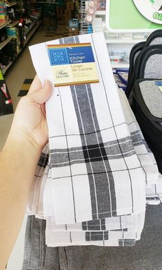 a person holding up some white and black cloths in a store with other items on the shelves