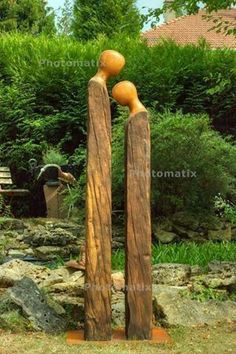 two wooden sculptures sitting in the middle of a garden