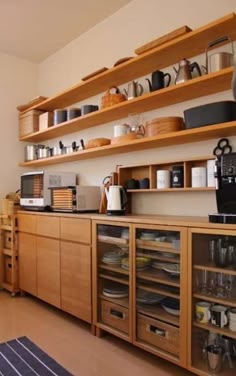 a kitchen with wooden shelves filled with dishes and coffee cups on top of it's counters